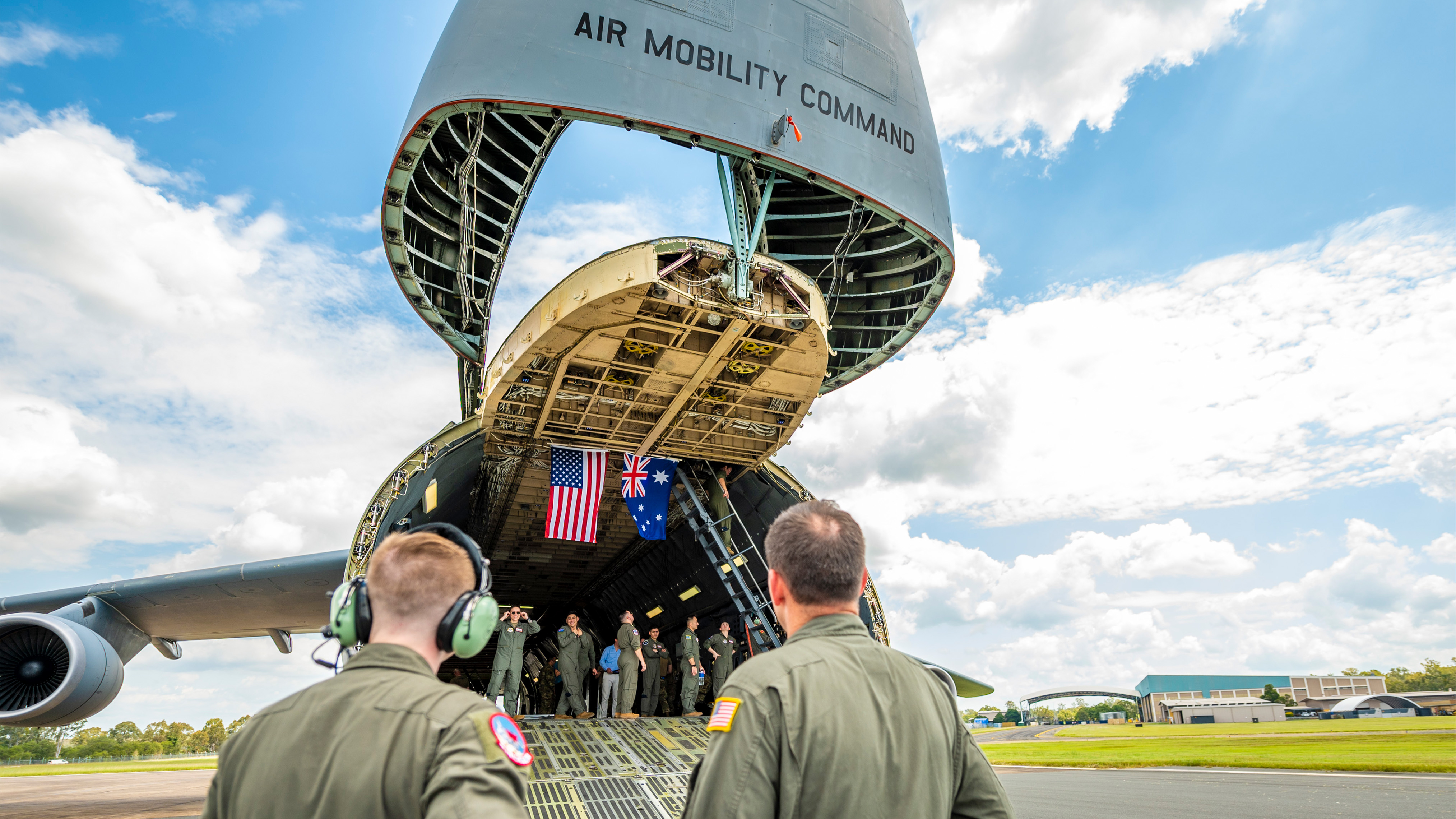 Service members walk towards the back of an open aircraft