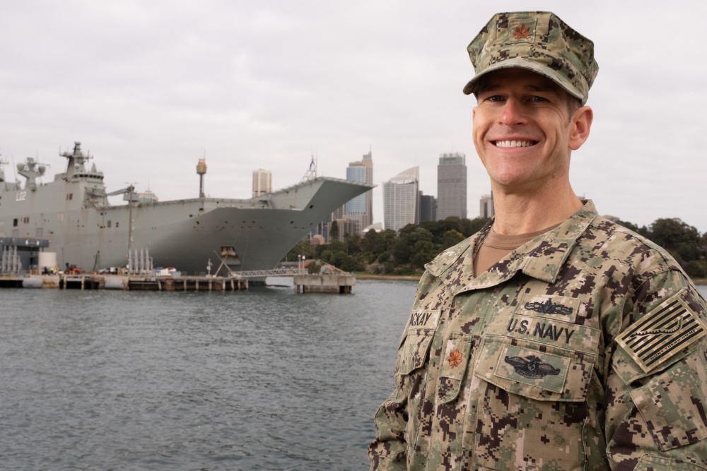 U.S. Navy Officer stands in front of military ship